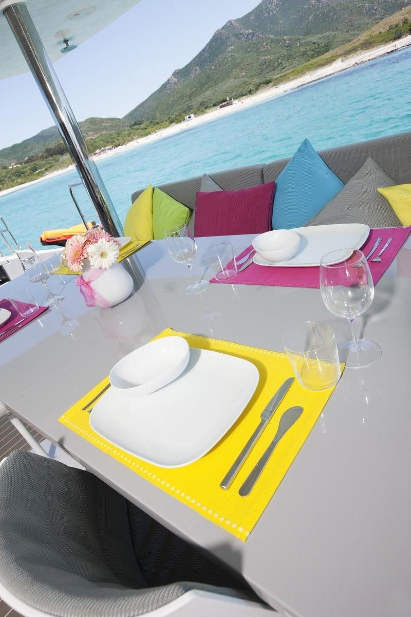 a table with a yellow plate and pink and white tablecloths with a yellow and white cloth aboard MAVERICK Yacht for Charter