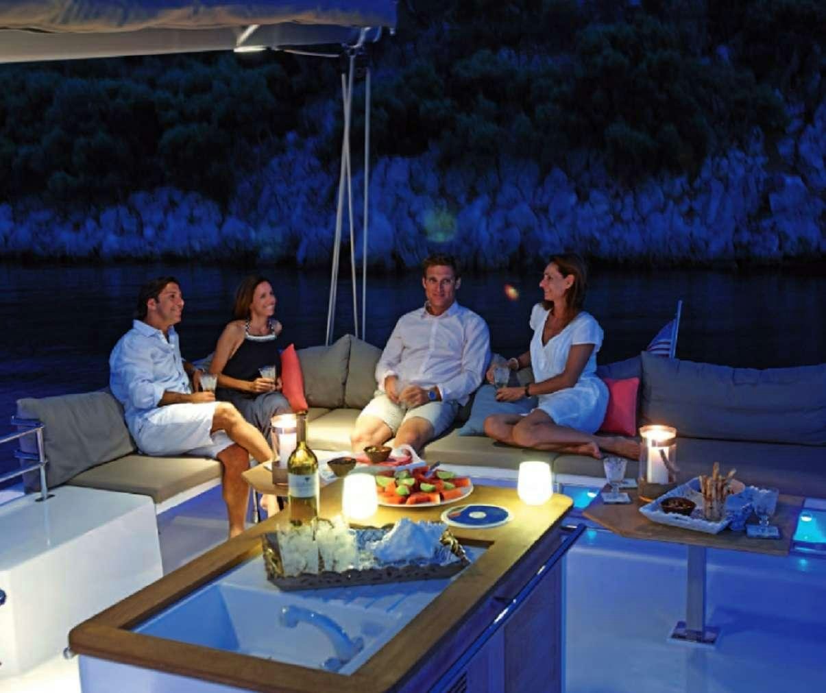 a group of people sitting on a boat with a view of a city at night aboard ENCHANTE Yacht for Charter