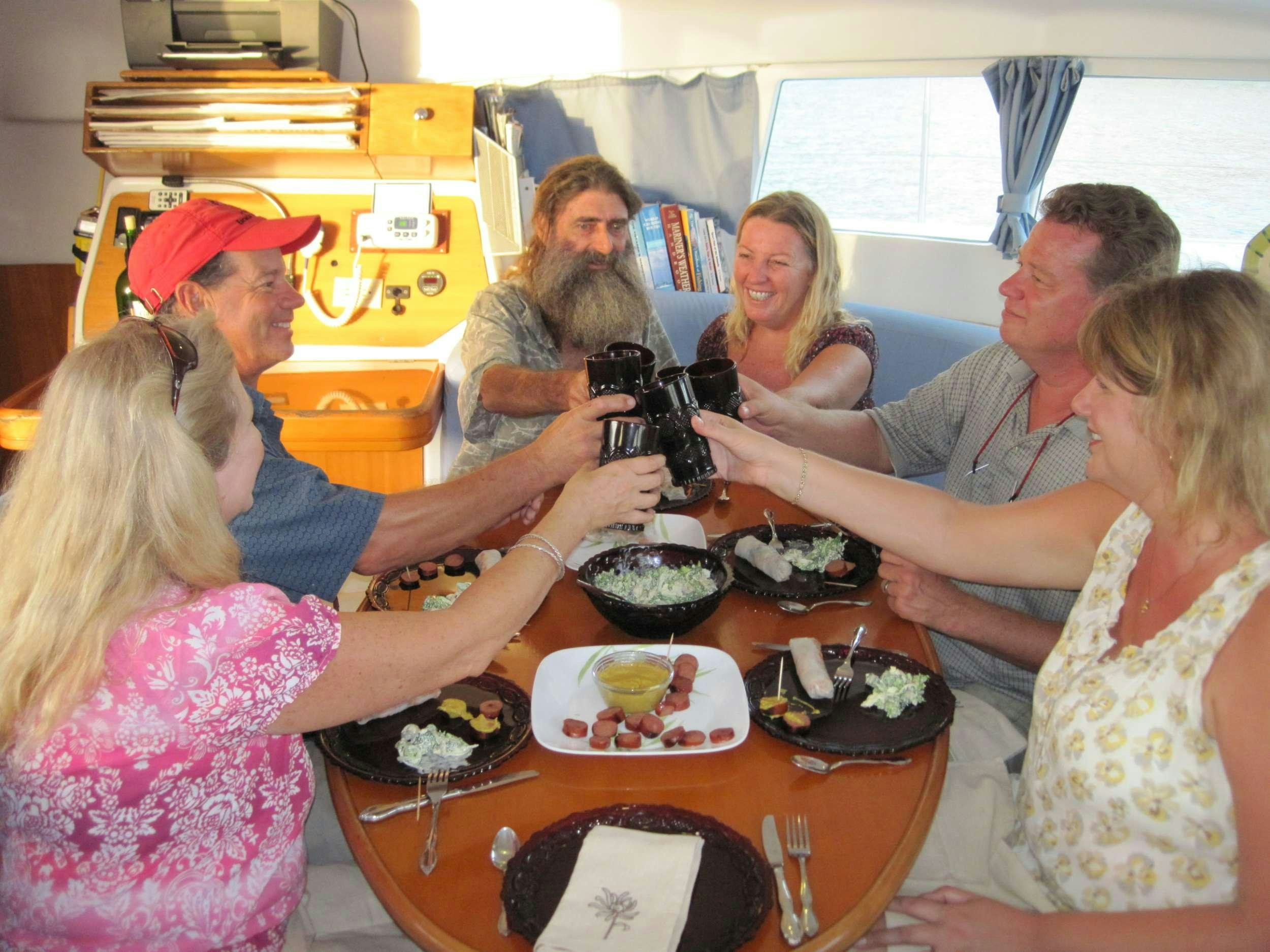 a group of people sitting around a table with food and a camera aboard GUIDING LIGHT Yacht for Charter
