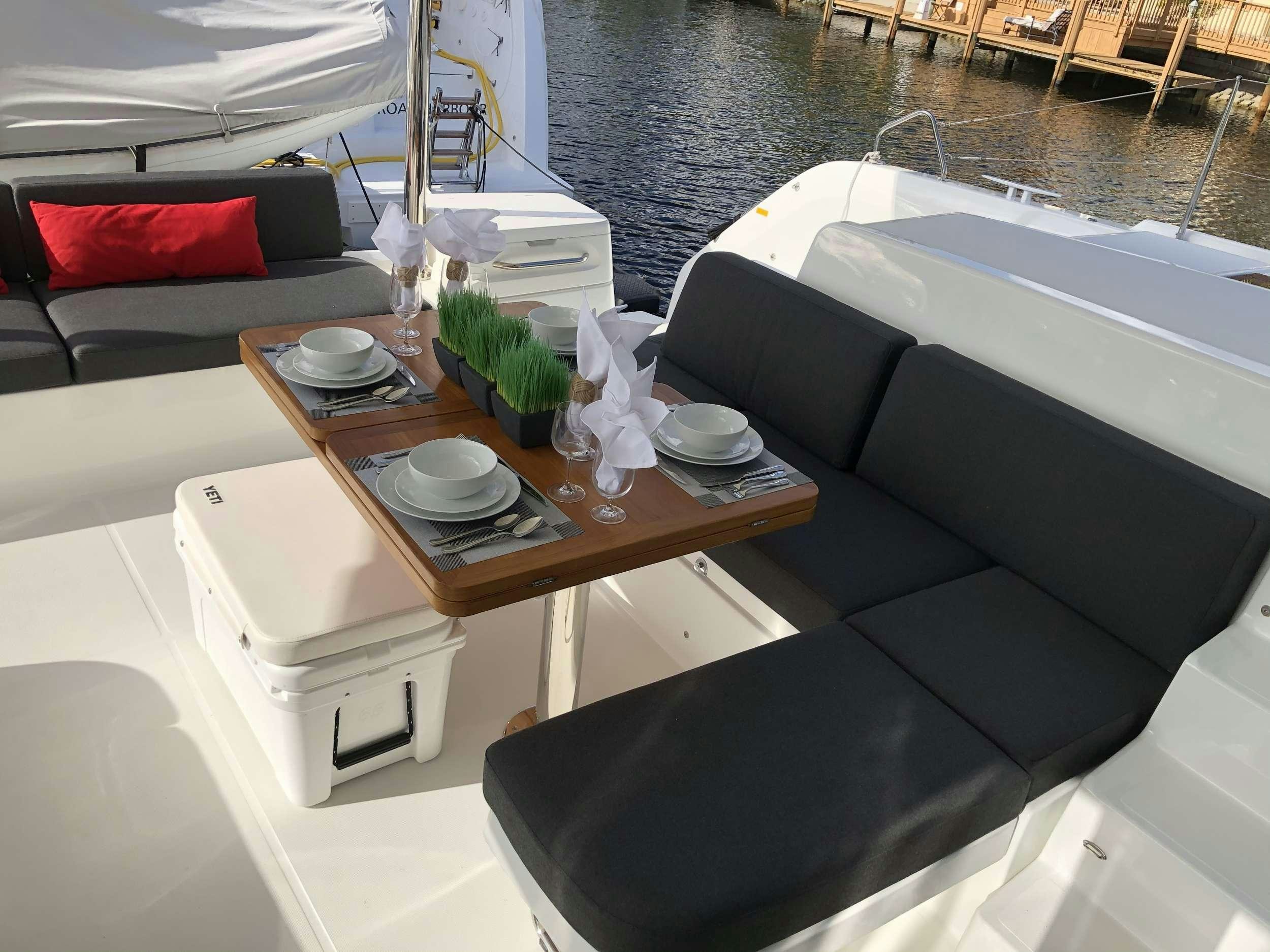 a room with a couch and a table with chairs and a table aboard SEA IO Yacht for Charter