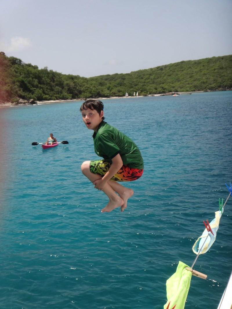 a boy jumping into the water aboard MANGO Yacht for Charter