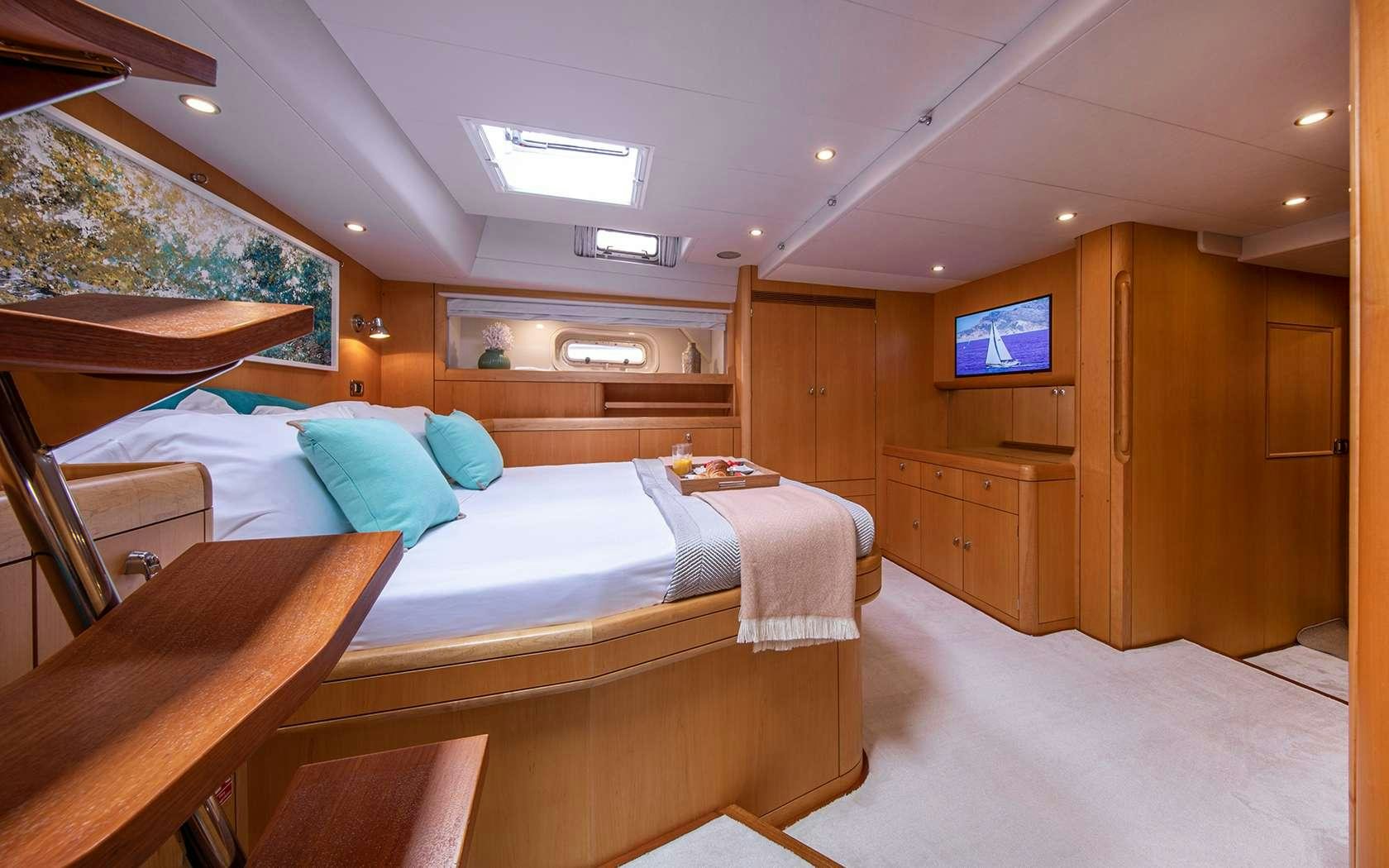 a room with a bed and a tv aboard BARE NECESSITIES Yacht for Charter