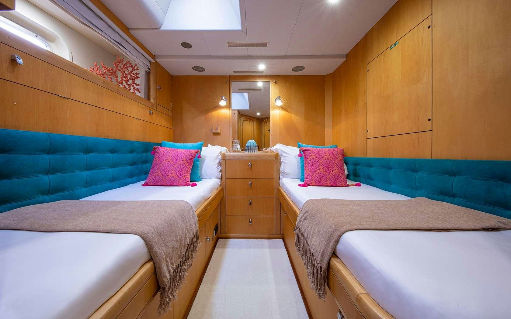 a room with beds and a tv aboard BARE NECESSITIES Yacht for Charter