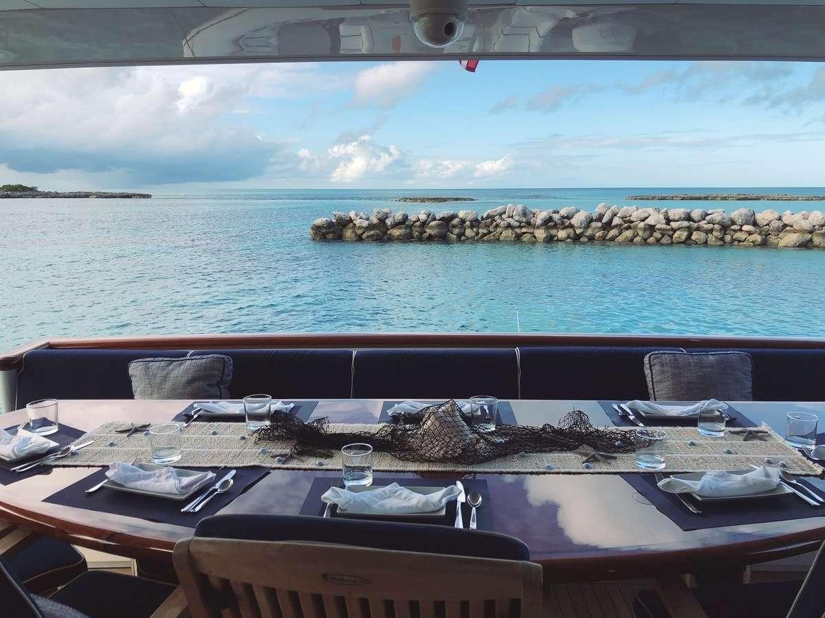 a table with plates and glasses on it by a body of water aboard ODIN Yacht for Charter