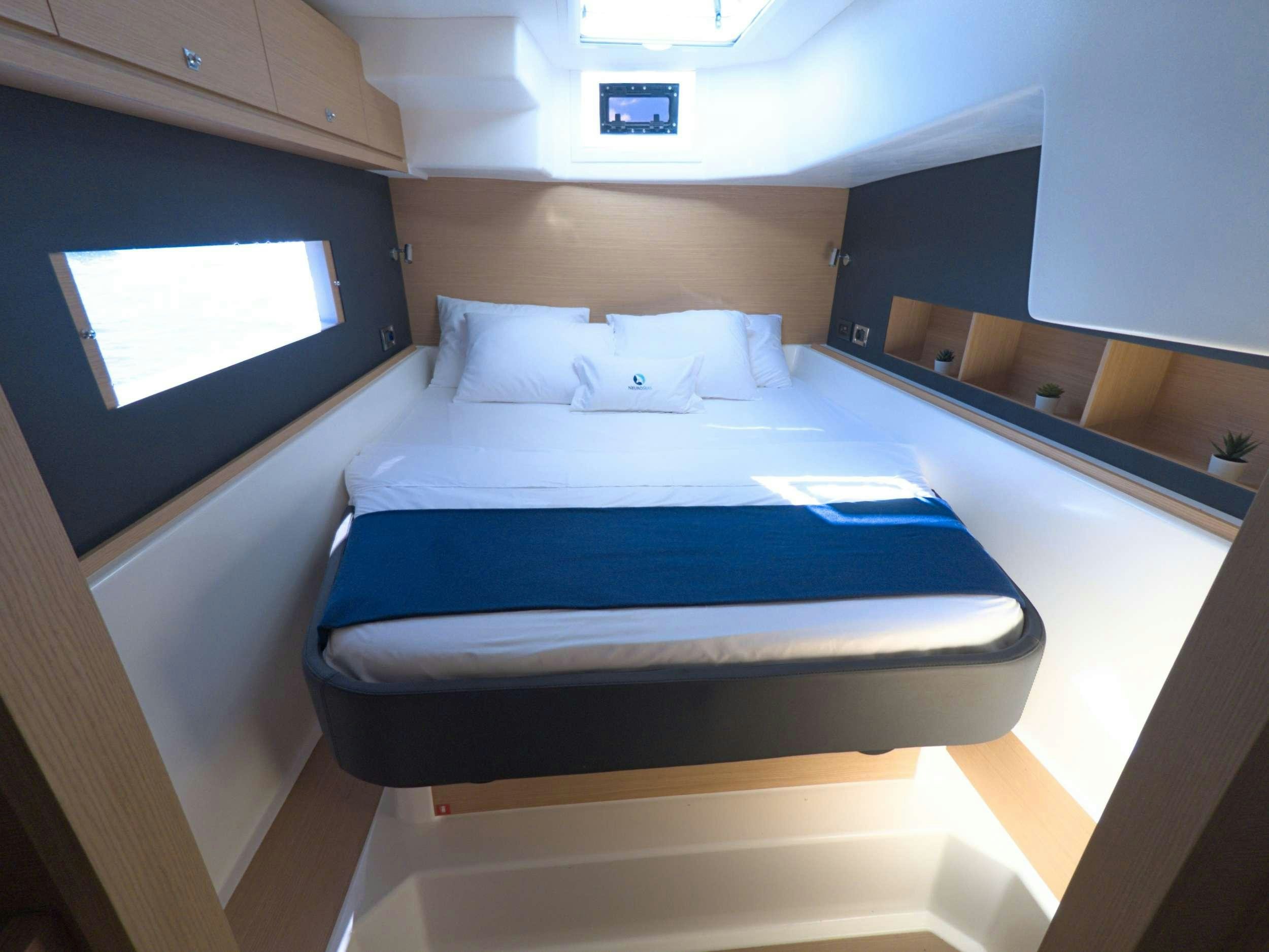 a bed with a blue sheet aboard NeuroSeas Yacht for Charter