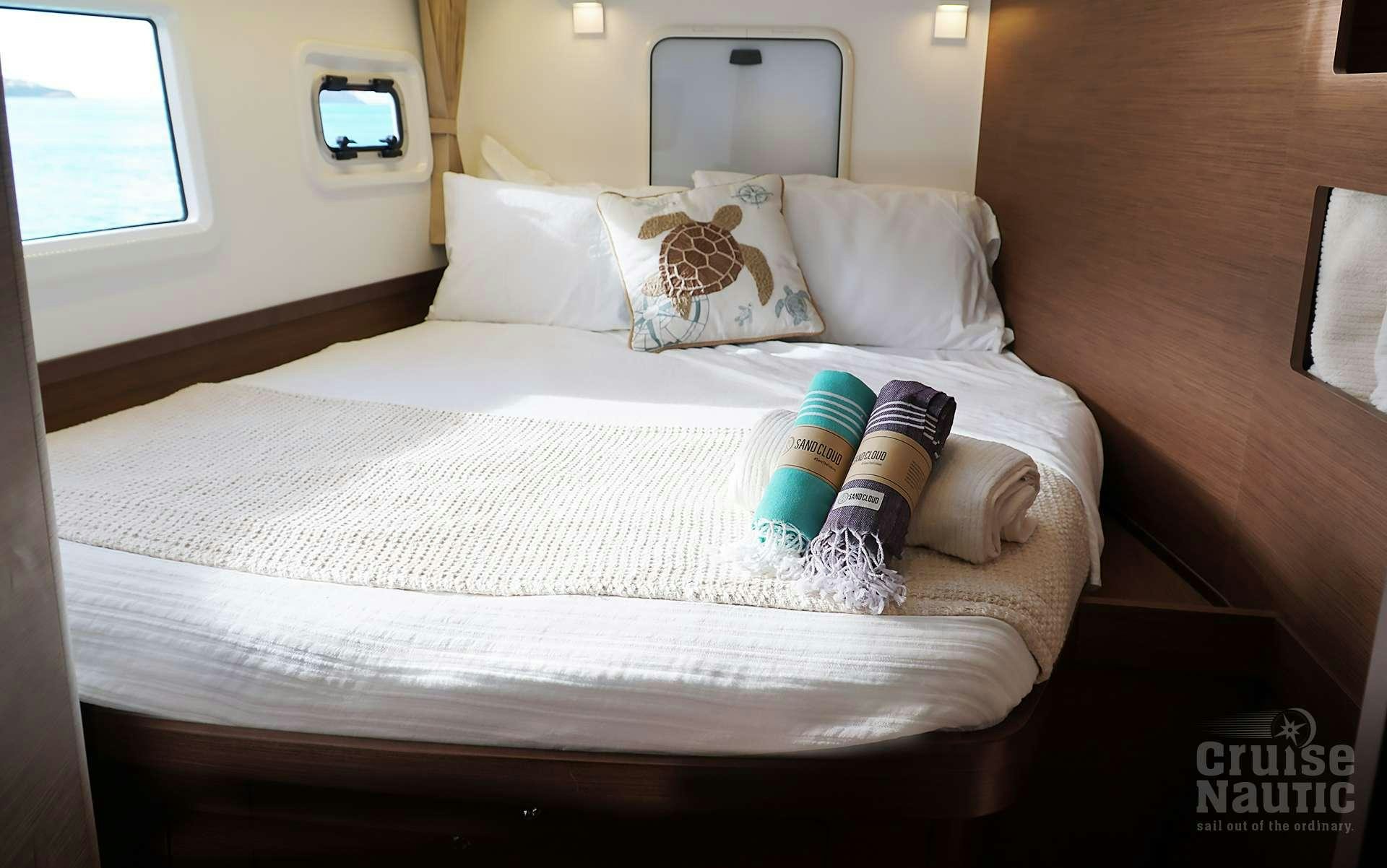 a bed with white sheets and pillows aboard CruiseNautic Yacht for Charter