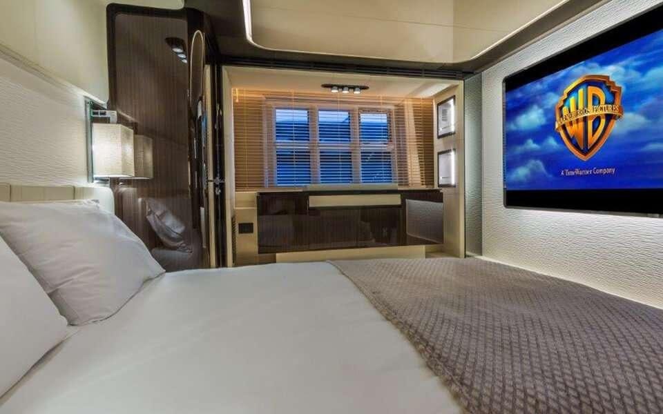 a bed with a screen on the wall aboard CARPE DIEM Yacht for Charter