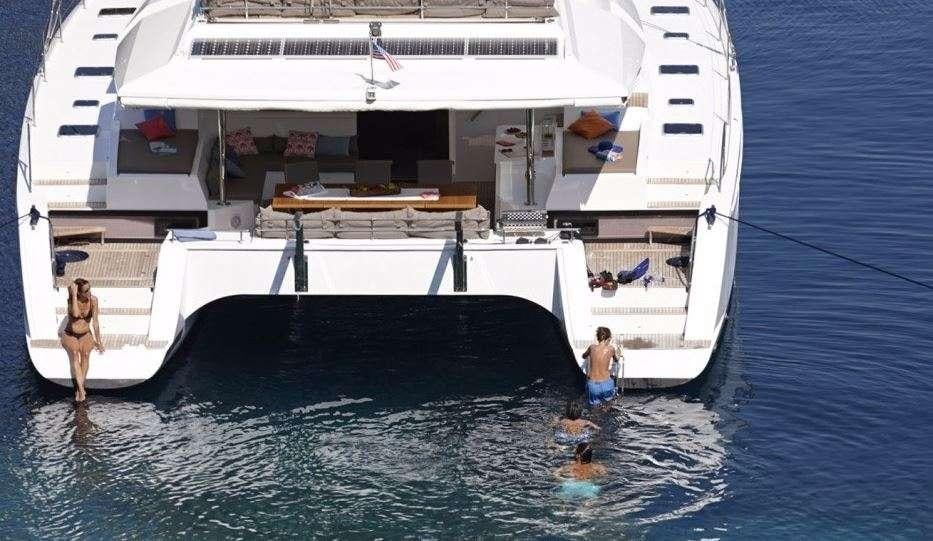 a group of people in a swimming pool next to a large white boat aboard DREAM TOBAGO Yacht for Charter