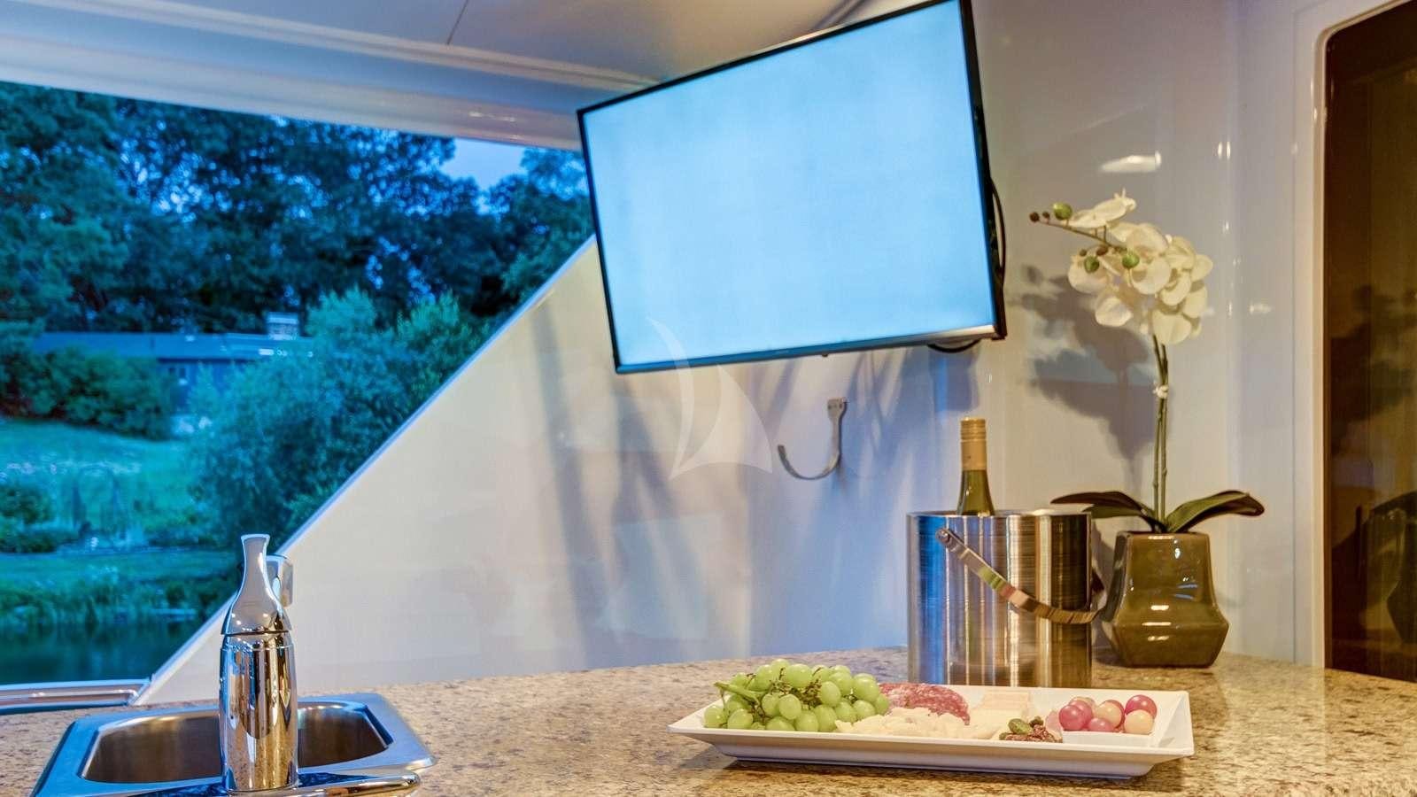 a table with a plate of food and a television on it aboard XOXO Yacht for Charter