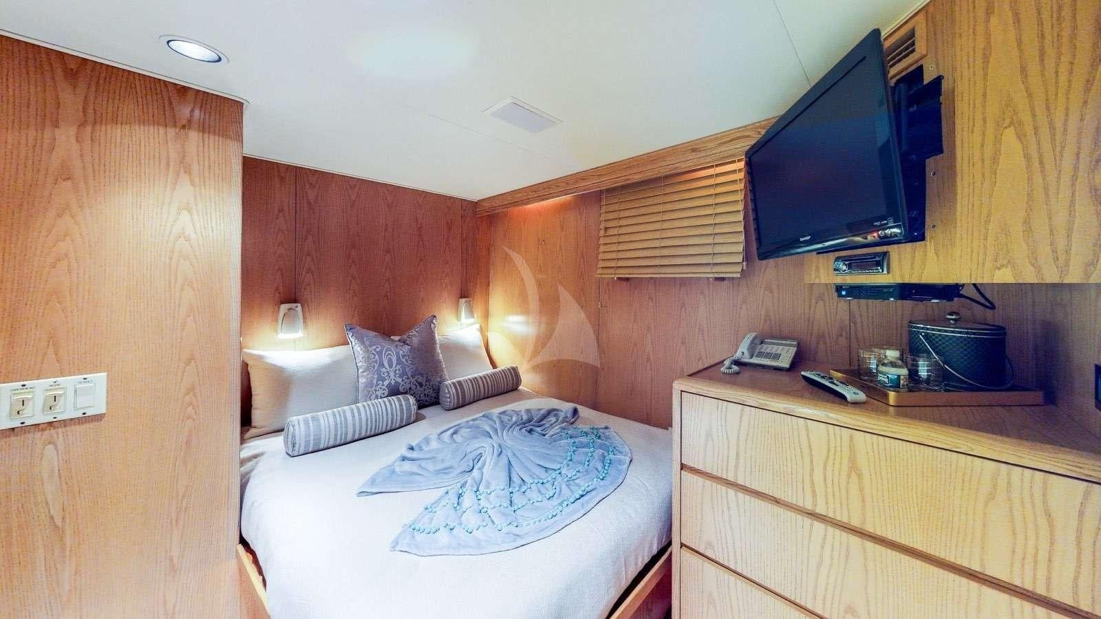 a room with a bed and a television aboard XOXO Yacht for Charter