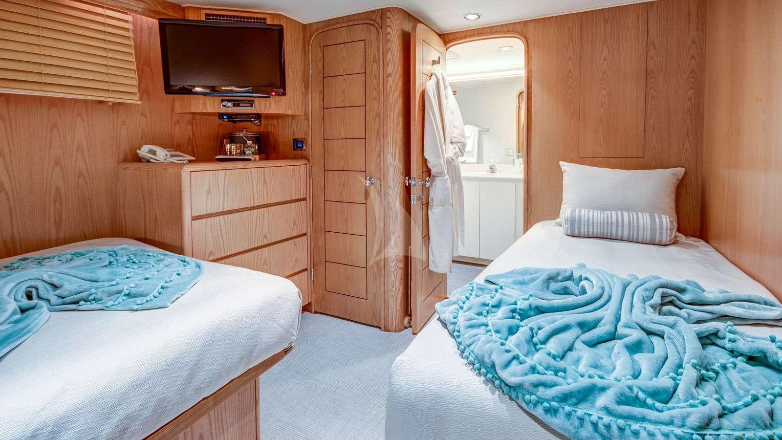 a room with a bed and a television aboard XOXO Yacht for Charter