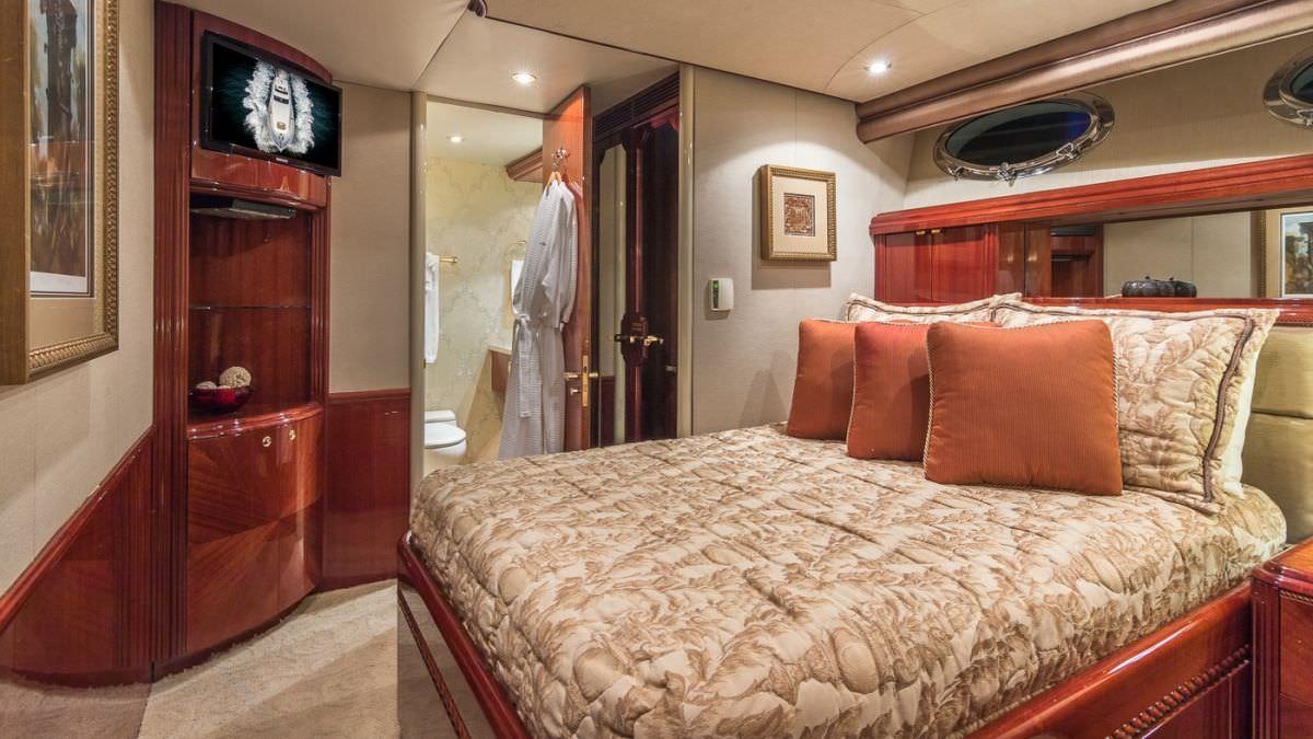 a bed with a white sheet and pillows in a room with a mirror aboard CEDAR ISLAND Yacht for Charter