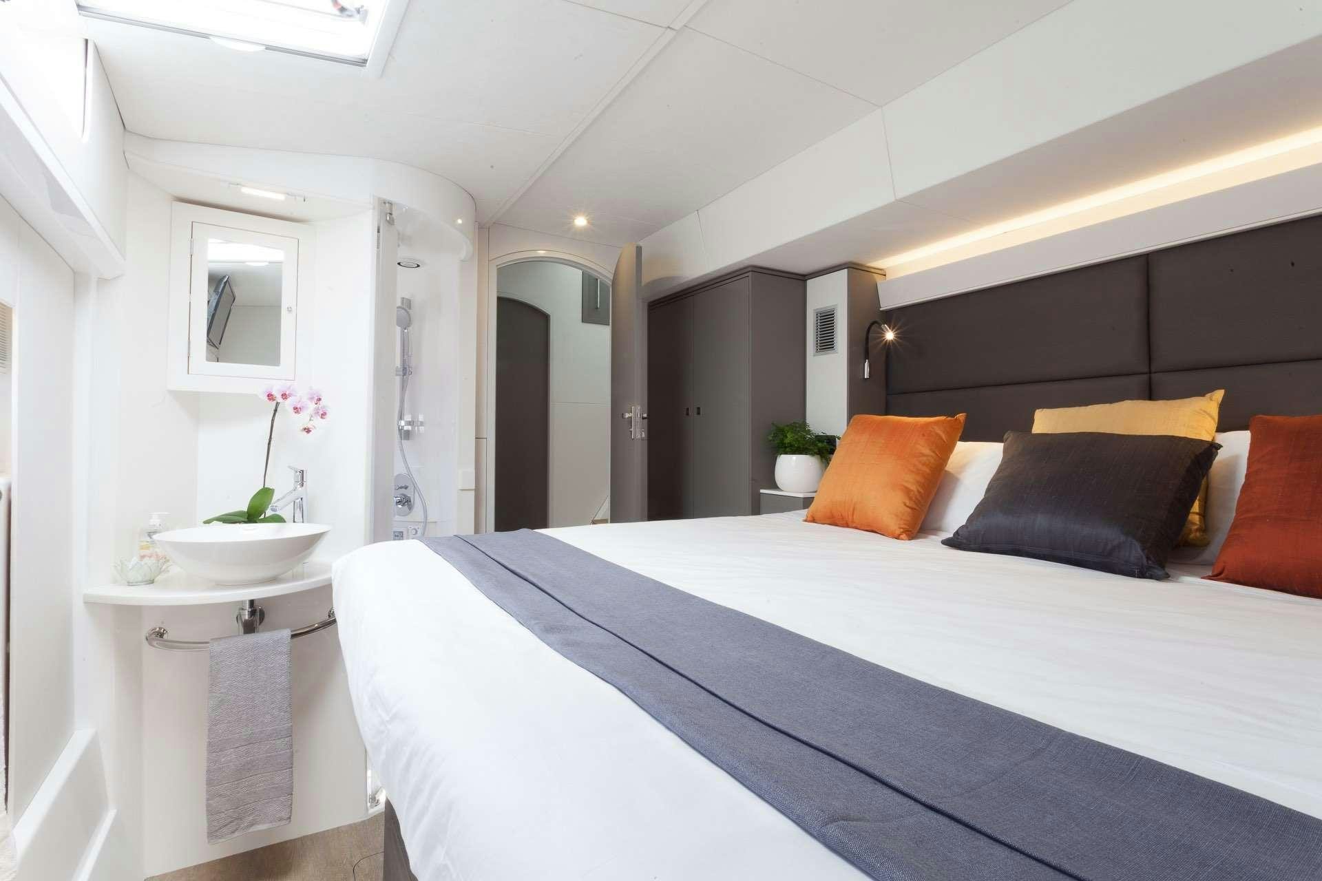 a bed with a white bed spread aboard VOYAGE 650 POWER CAT Yacht for Charter