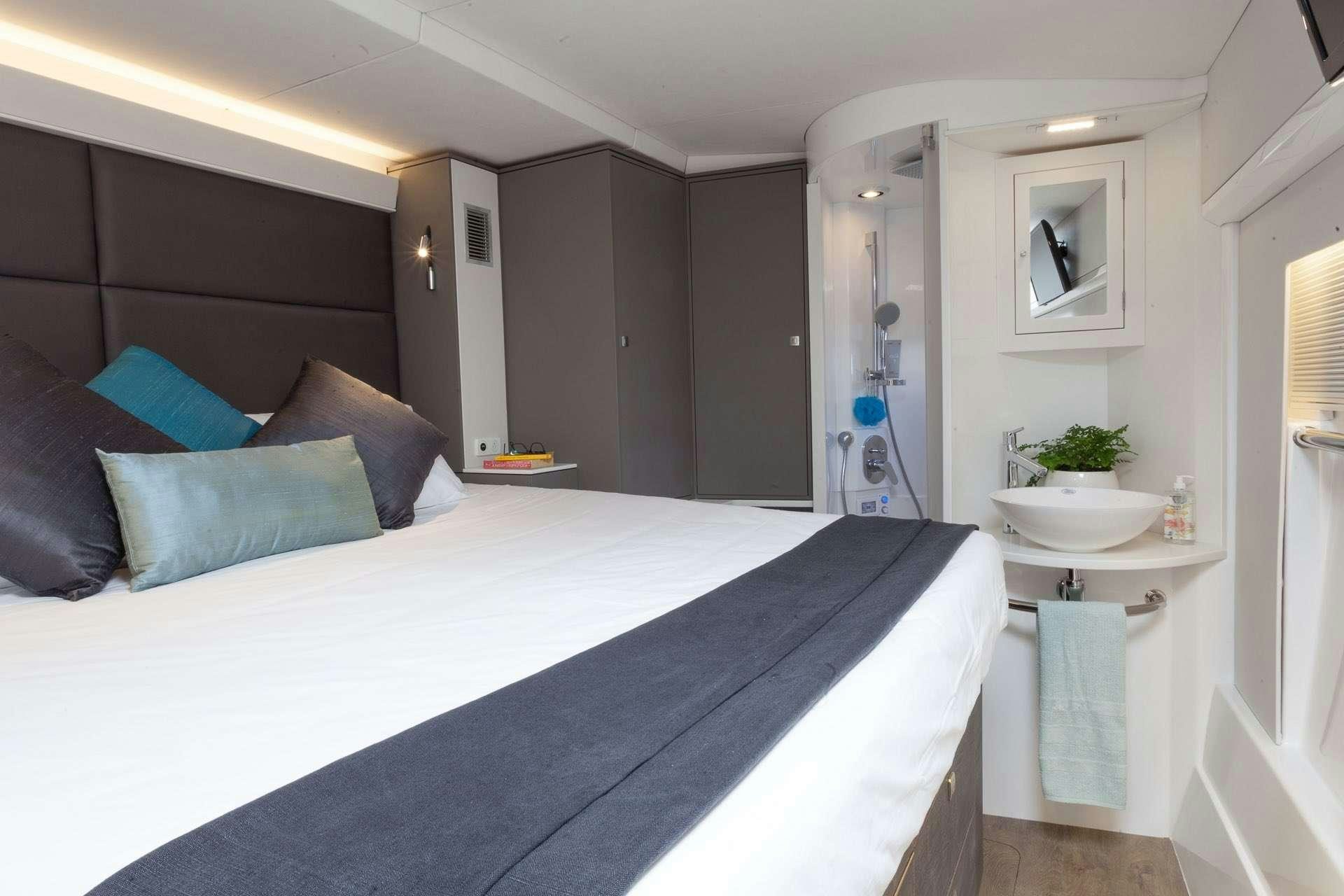 a bed with a blue bed spread aboard VOYAGE 650 POWER CAT Yacht for Charter