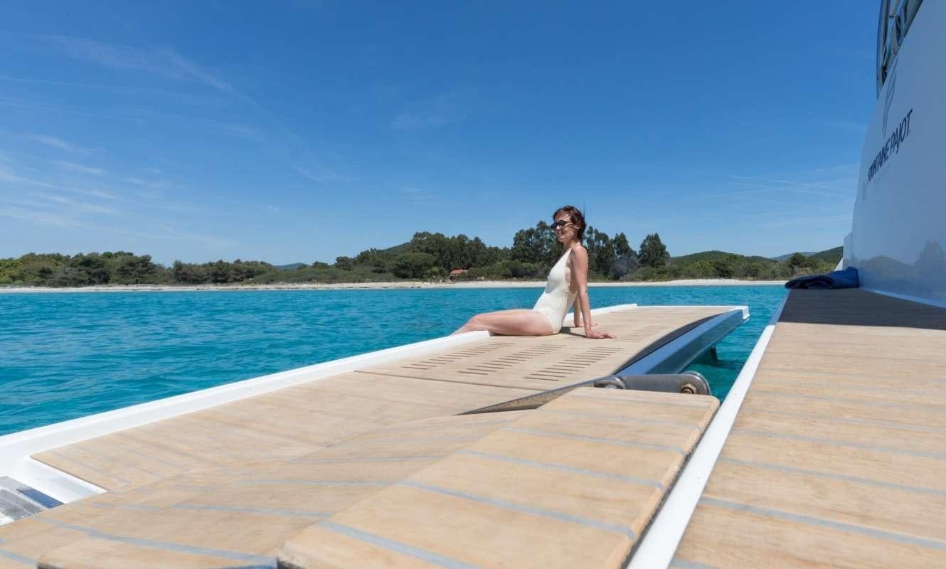 a person sitting on a lounge chair on a dock by the water aboard Hondo Yacht for Charter