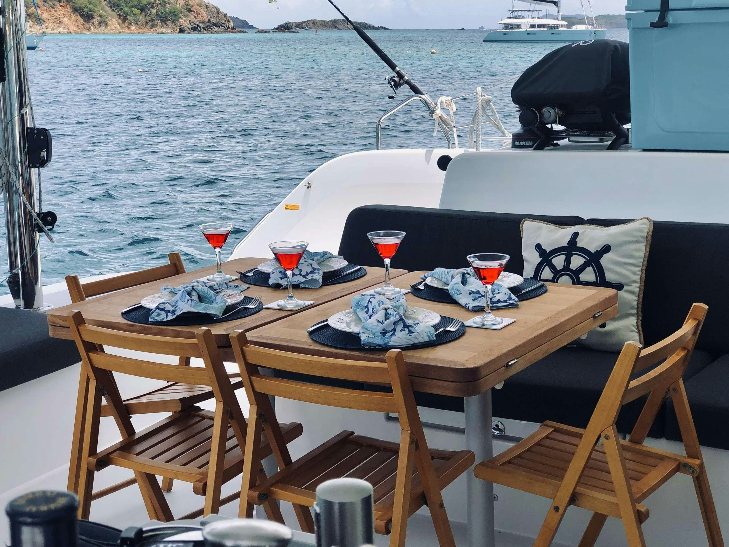 a table with glasses and food on it by a body of water aboard NAUTI CAT Yacht for Charter