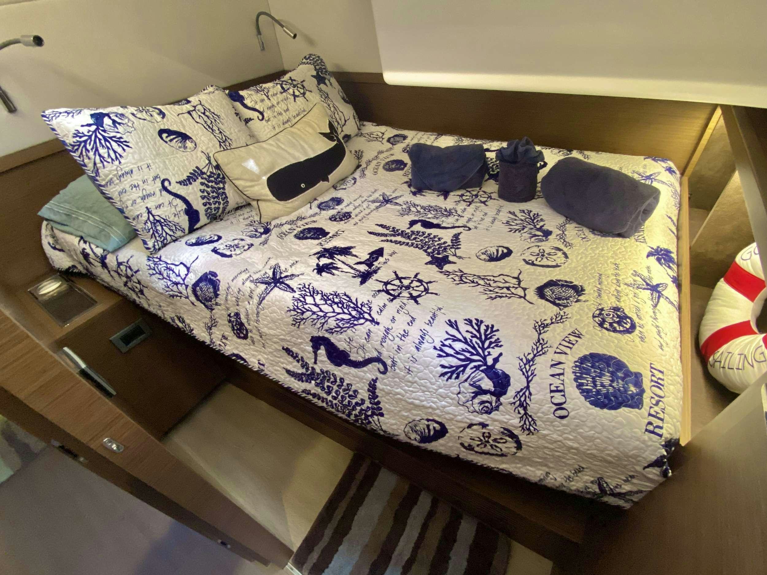 a bed with blue and white sheets aboard NAUTI CAT Yacht for Charter