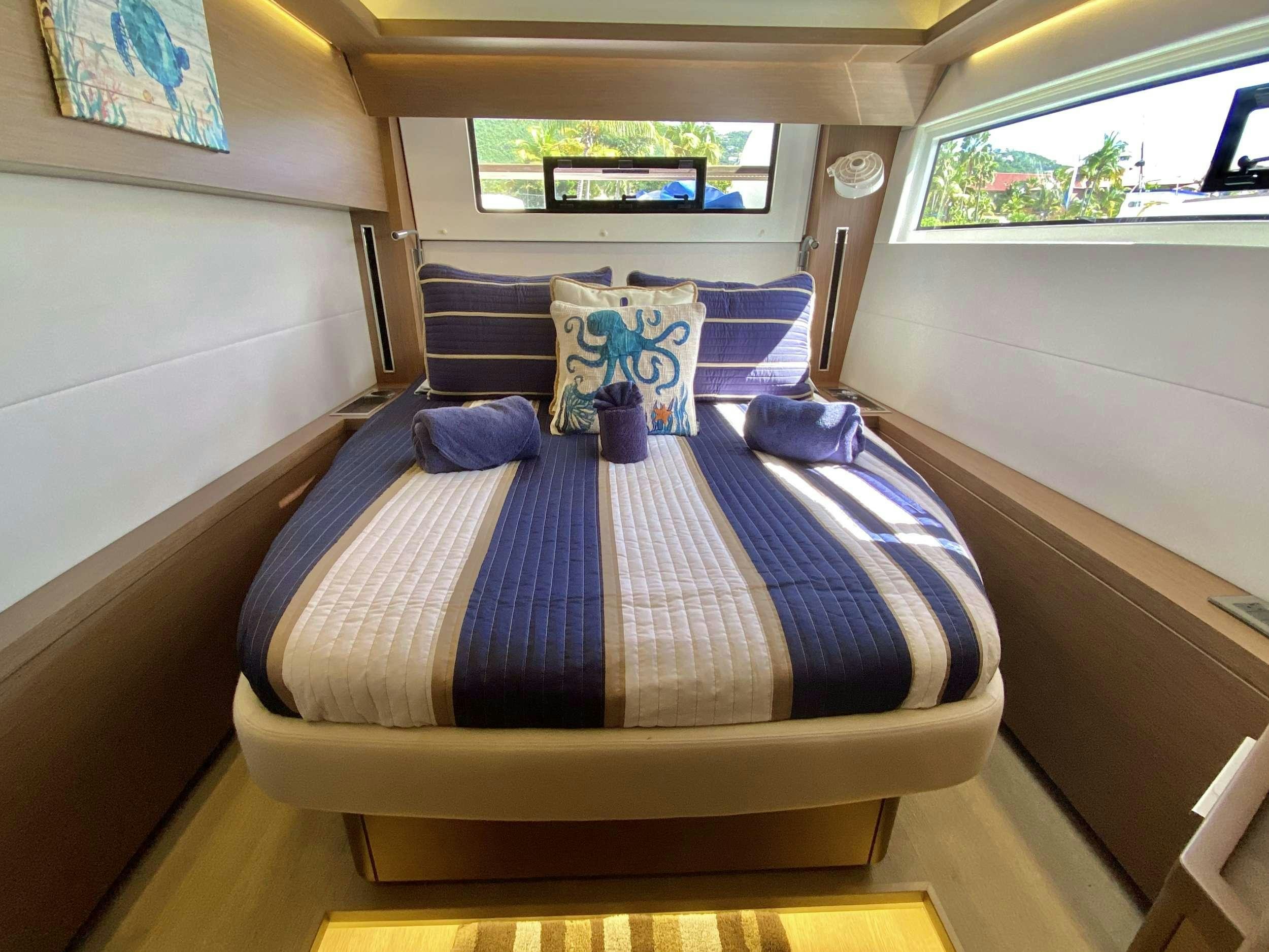 a bed with blue sheets aboard NAUTI CAT Yacht for Charter