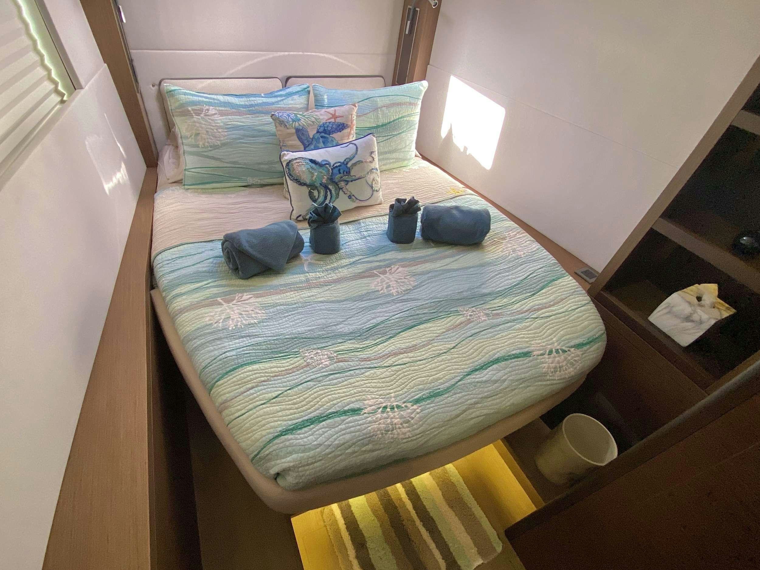 a bed with blue sheets aboard NAUTI CAT Yacht for Charter