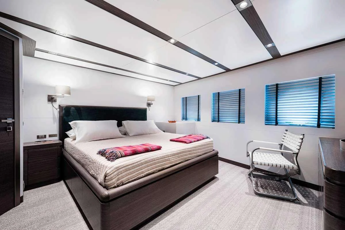a bedroom with a bed and a chair aboard GENESIA Yacht for Charter