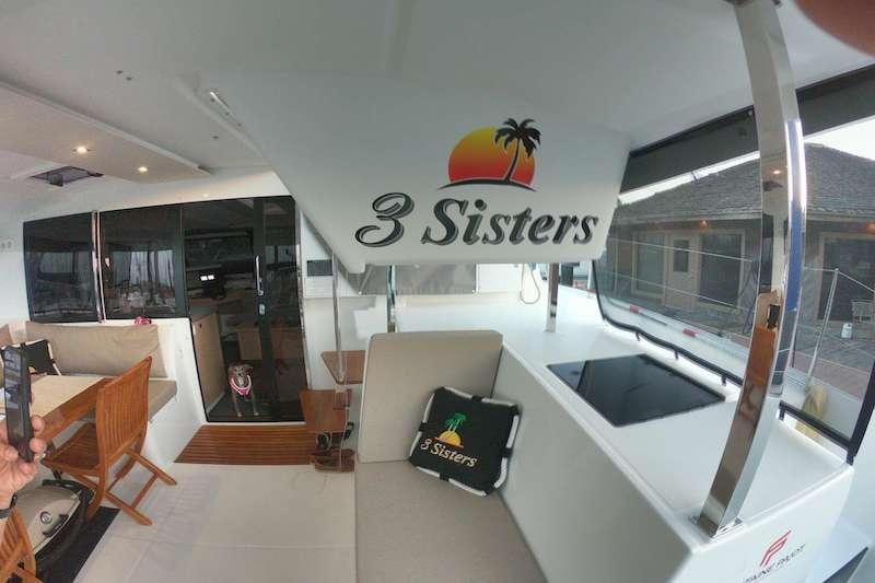 a room with a large window and a couch and a table with chairs aboard 3 SISTERS Yacht for Charter