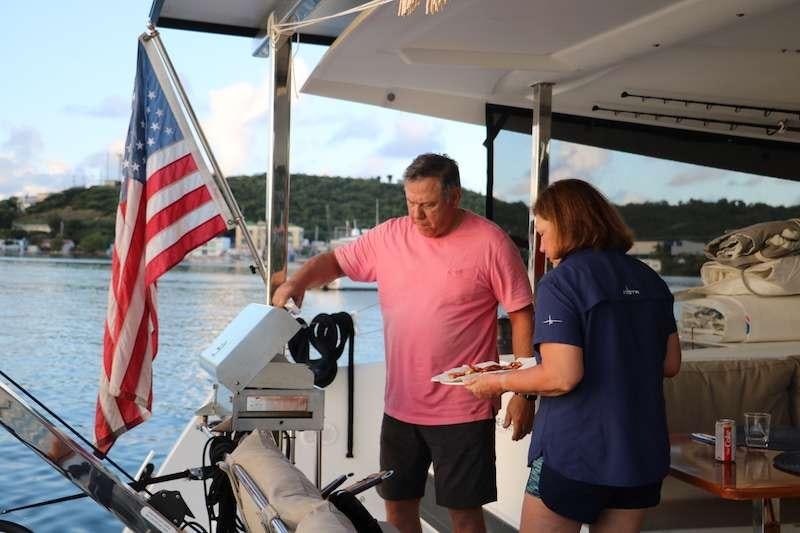 a man and woman standing on a boat with a flag aboard 3 SISTERS Yacht for Charter