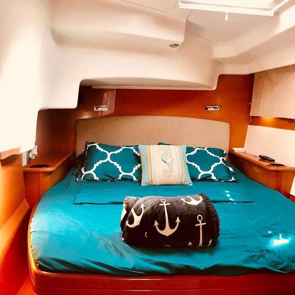 a bed with a blue comforter and pillows aboard BLACK SHEEP Yacht for Charter