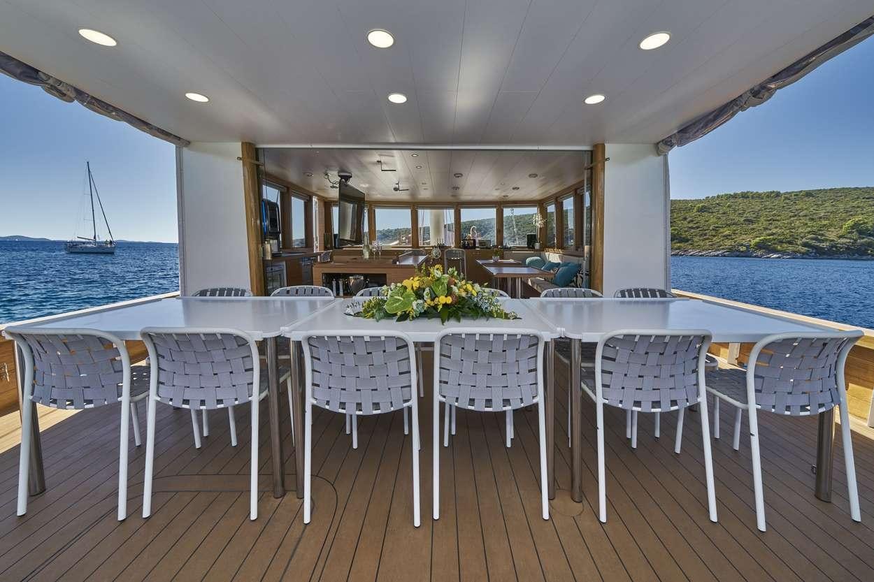 a large dining room with a large body of water and a patio with chairs and tables aboard ARDURA Yacht for Charter