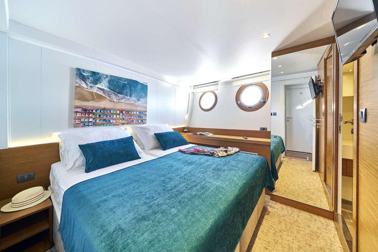 a bedroom with a bed and a desk aboard ARDURA Yacht for Charter
