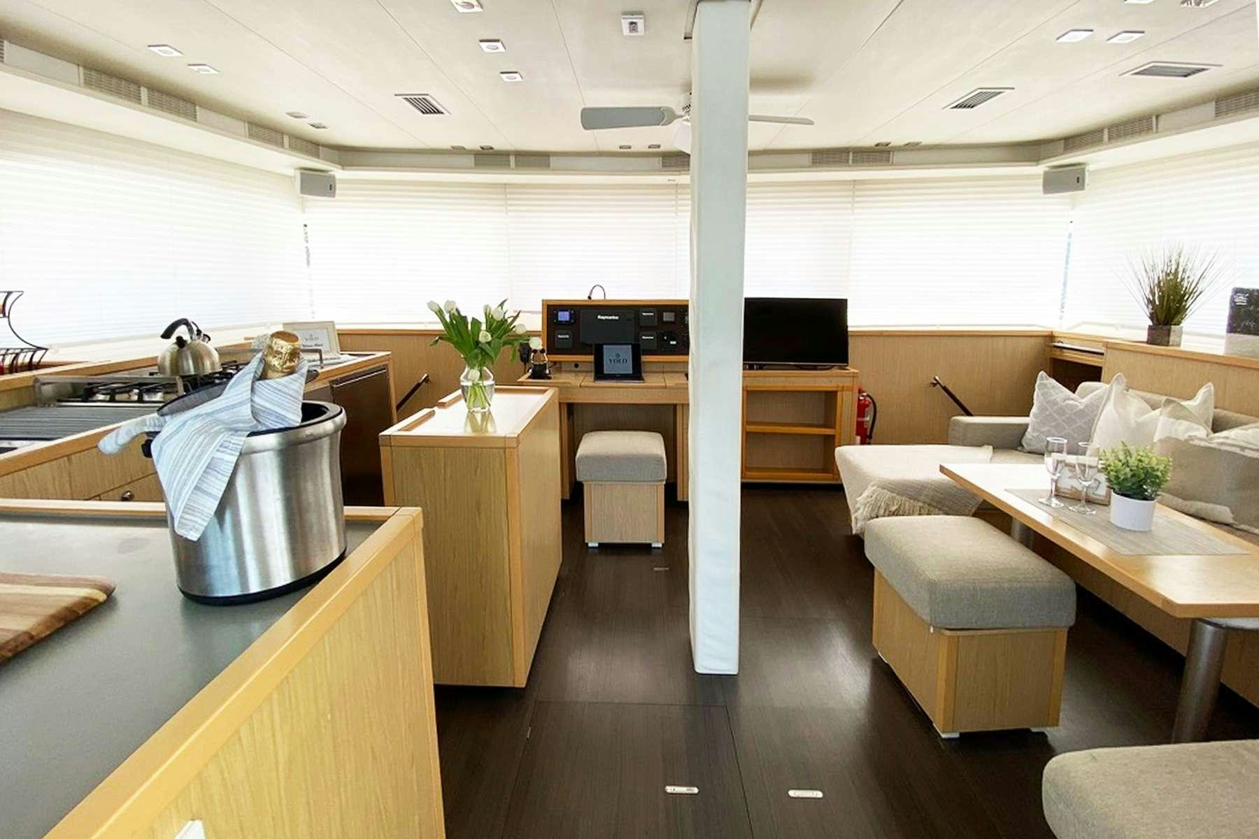 a room with a couch and a table and a potted plant aboard YOLO II Yacht for Charter
