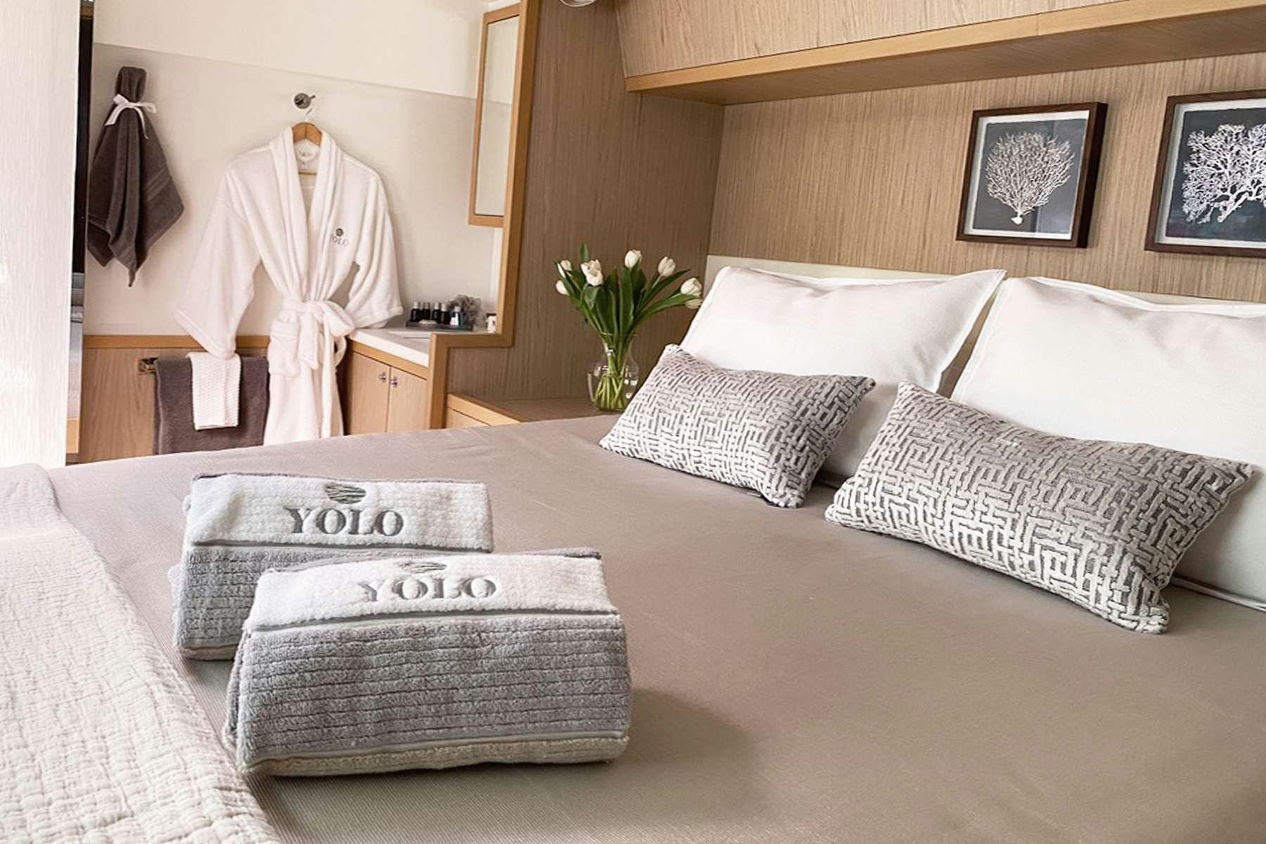 a bed with pillows and a robe aboard YOLO II Yacht for Charter