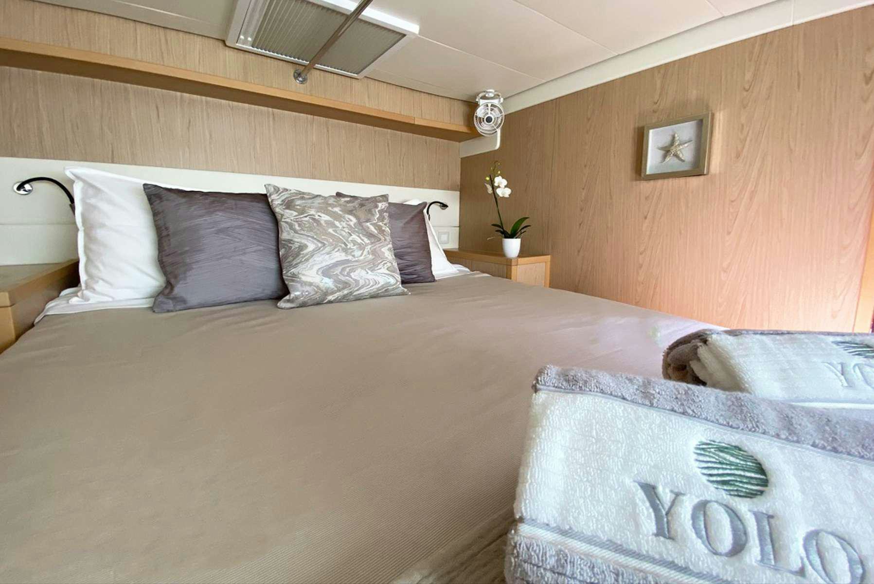 a bed with a white comforter aboard YOLO II Yacht for Charter