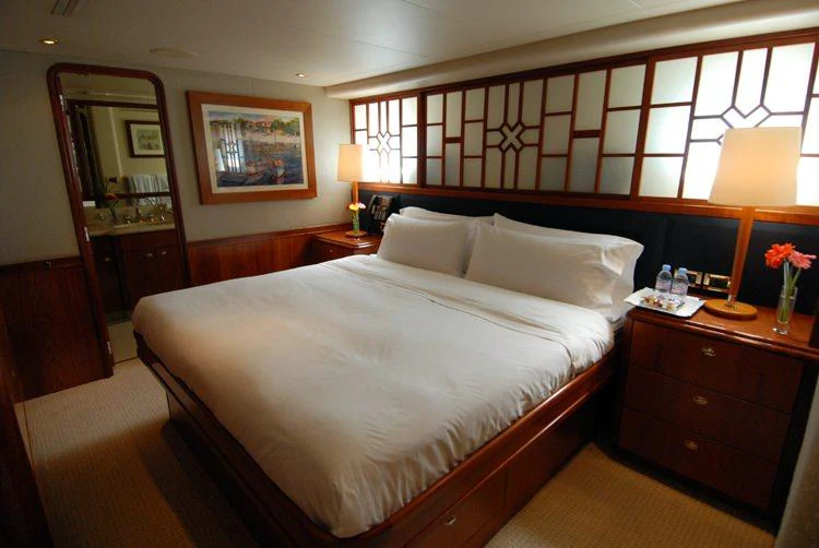 a bed with white sheets and pillows aboard DONA LOLA Yacht for Charter