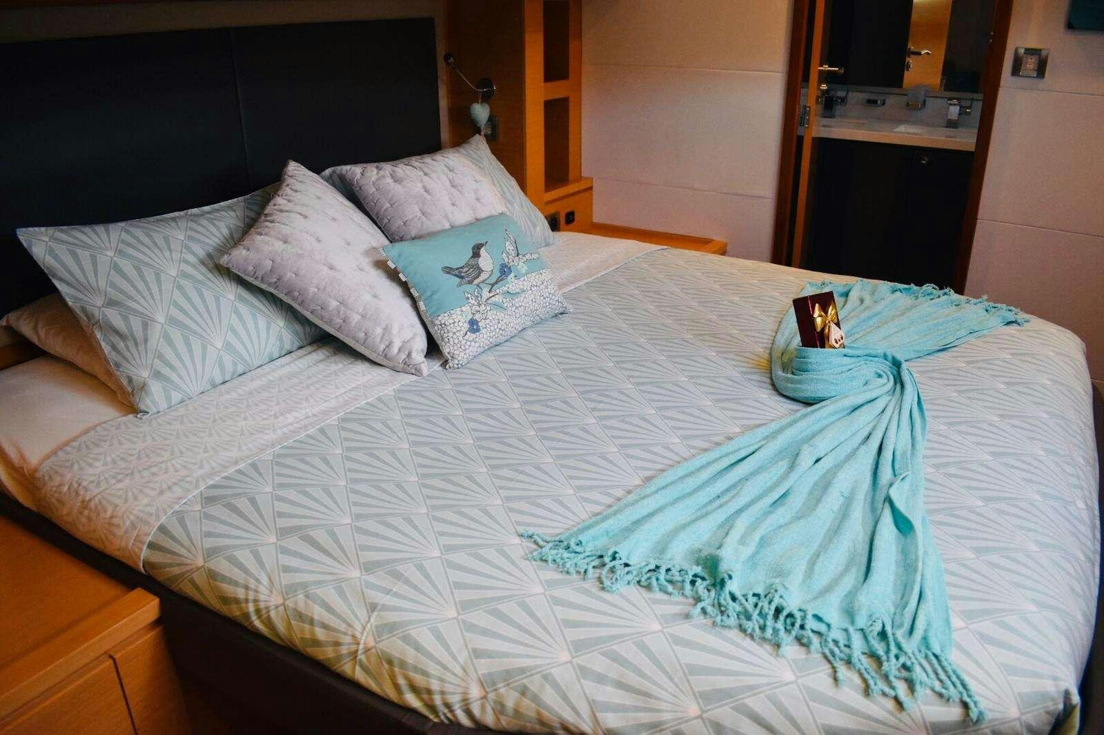 a bed with a blue sheet and pillows aboard LIR Yacht for Charter