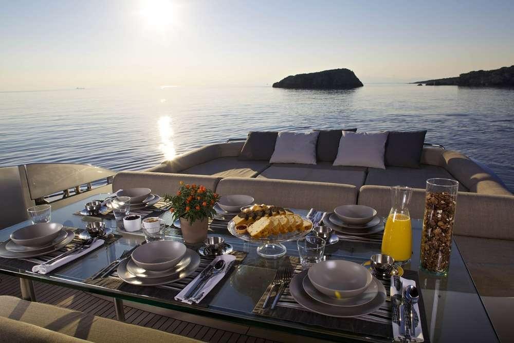 a table with food and drinks on it by a large body of water aboard SOLARIS Yacht for Charter