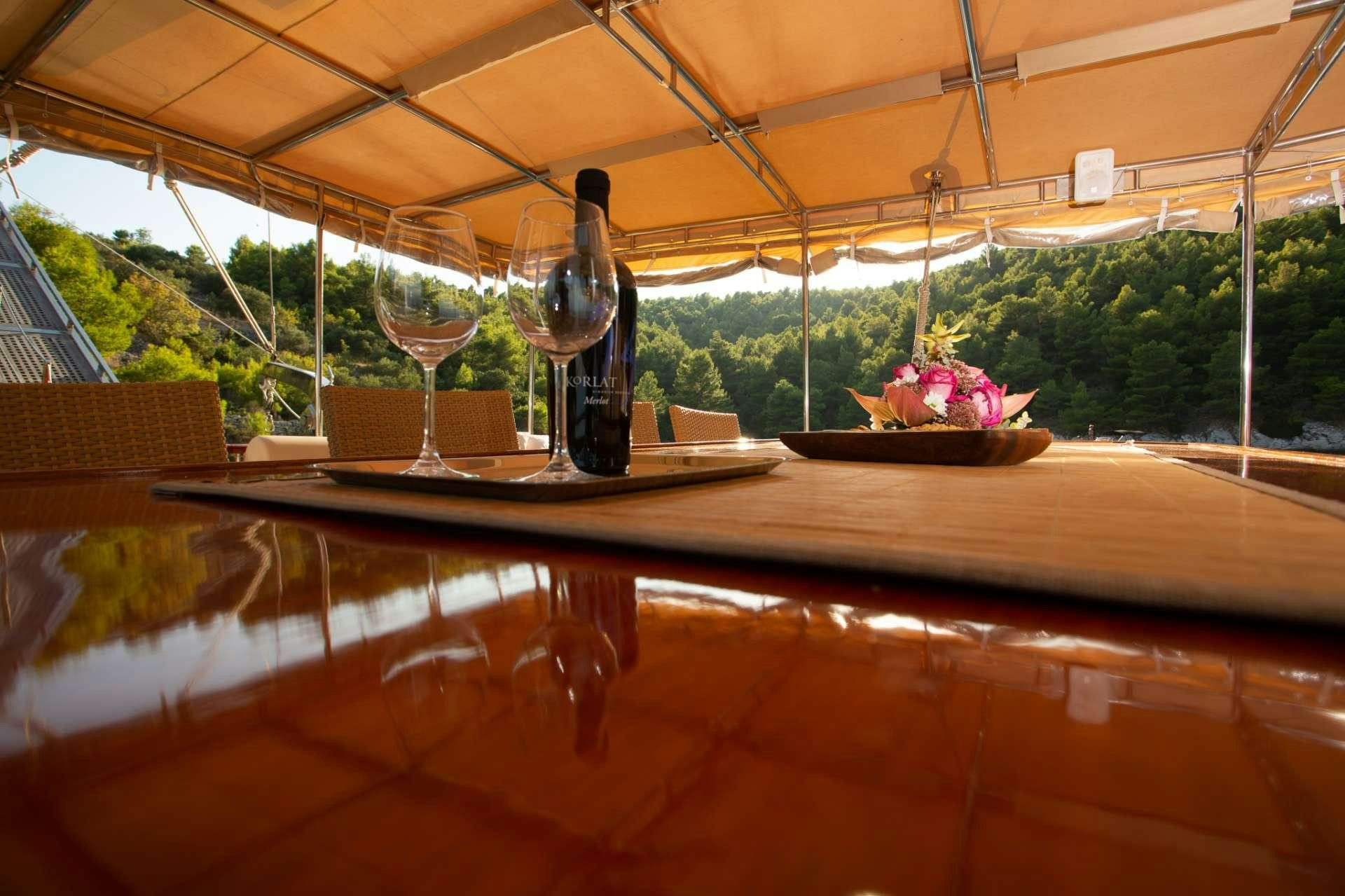 a table with a glass and a vase with flowers on it aboard Malena Yacht for Charter