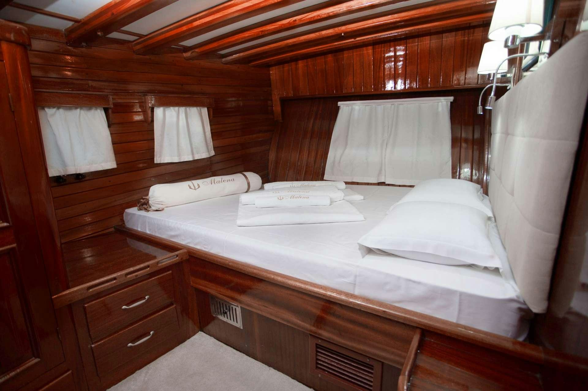 a room with a bed and a dresser aboard Malena Yacht for Charter