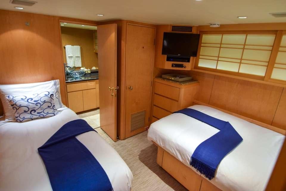 a room with beds and a tv aboard ISLAND VIBES Yacht for Charter