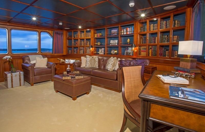a living room with a large book shelf and a leather couch aboard LADY VICTORIA Yacht for Charter