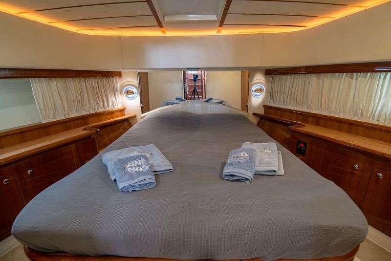 a bed with a blue sheet and a pillow on it aboard ANANAS Yacht for Charter