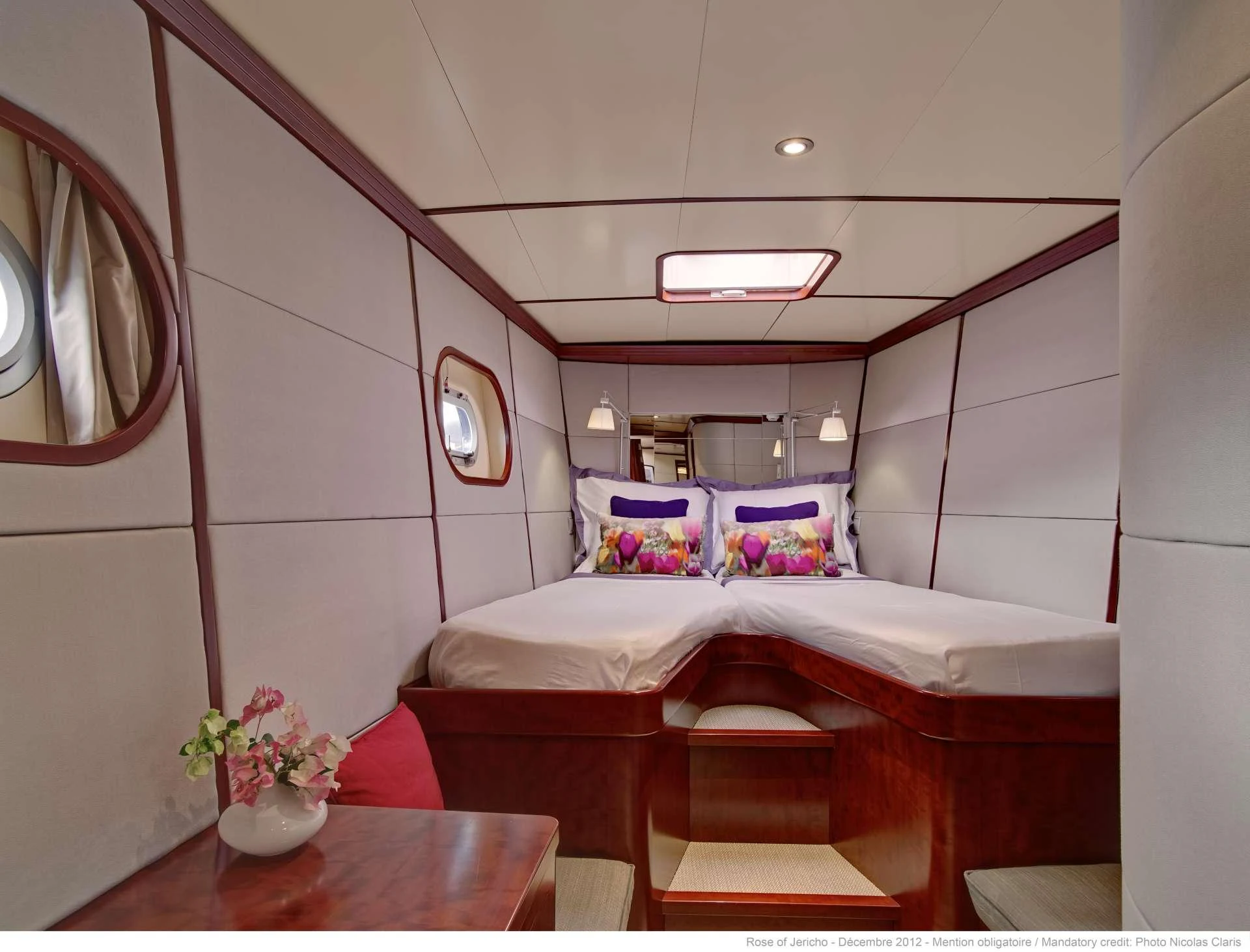 The guest stateroom features twin beds with vibrant floral accents and elegant wood finishes. aboard AZIZAM Yacht for Charter