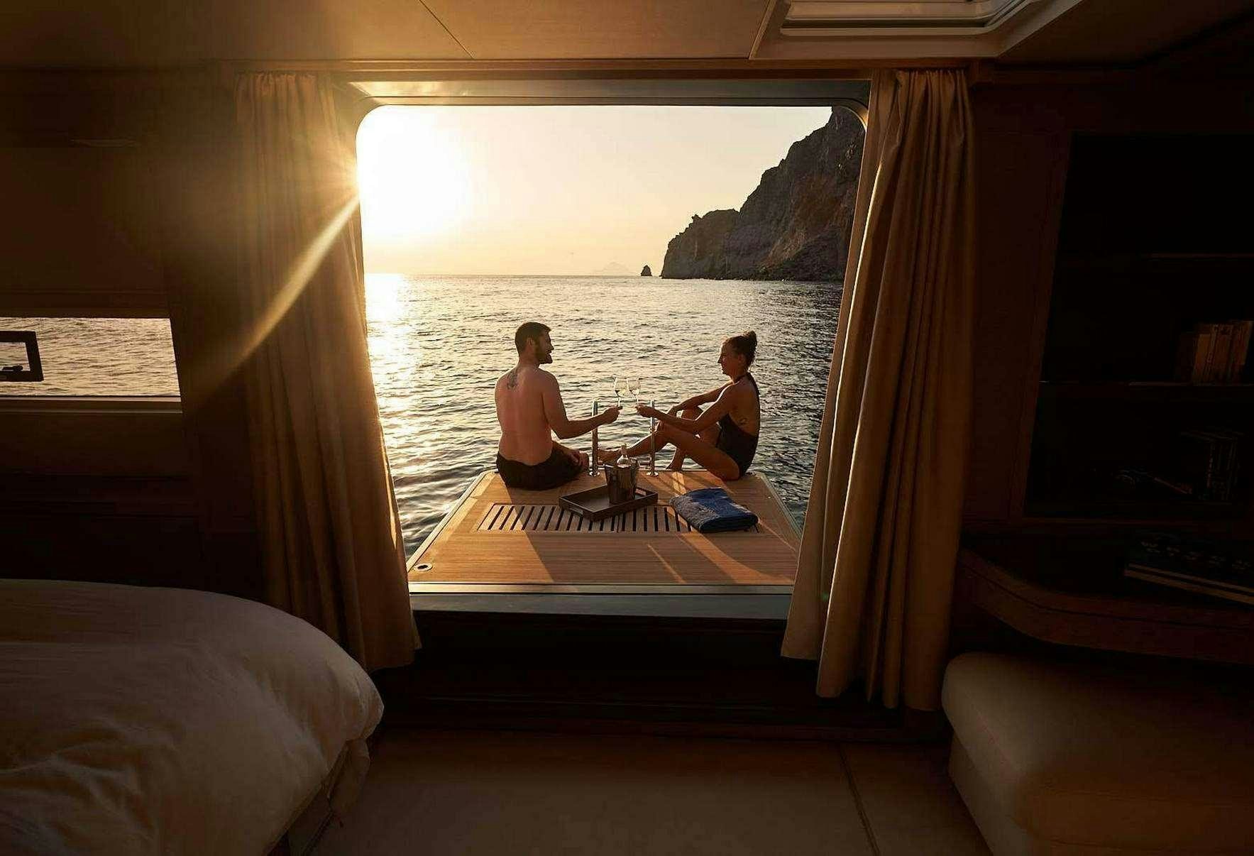 a couple of people sitting on a bed looking out a window aboard BABAC Yacht for Charter