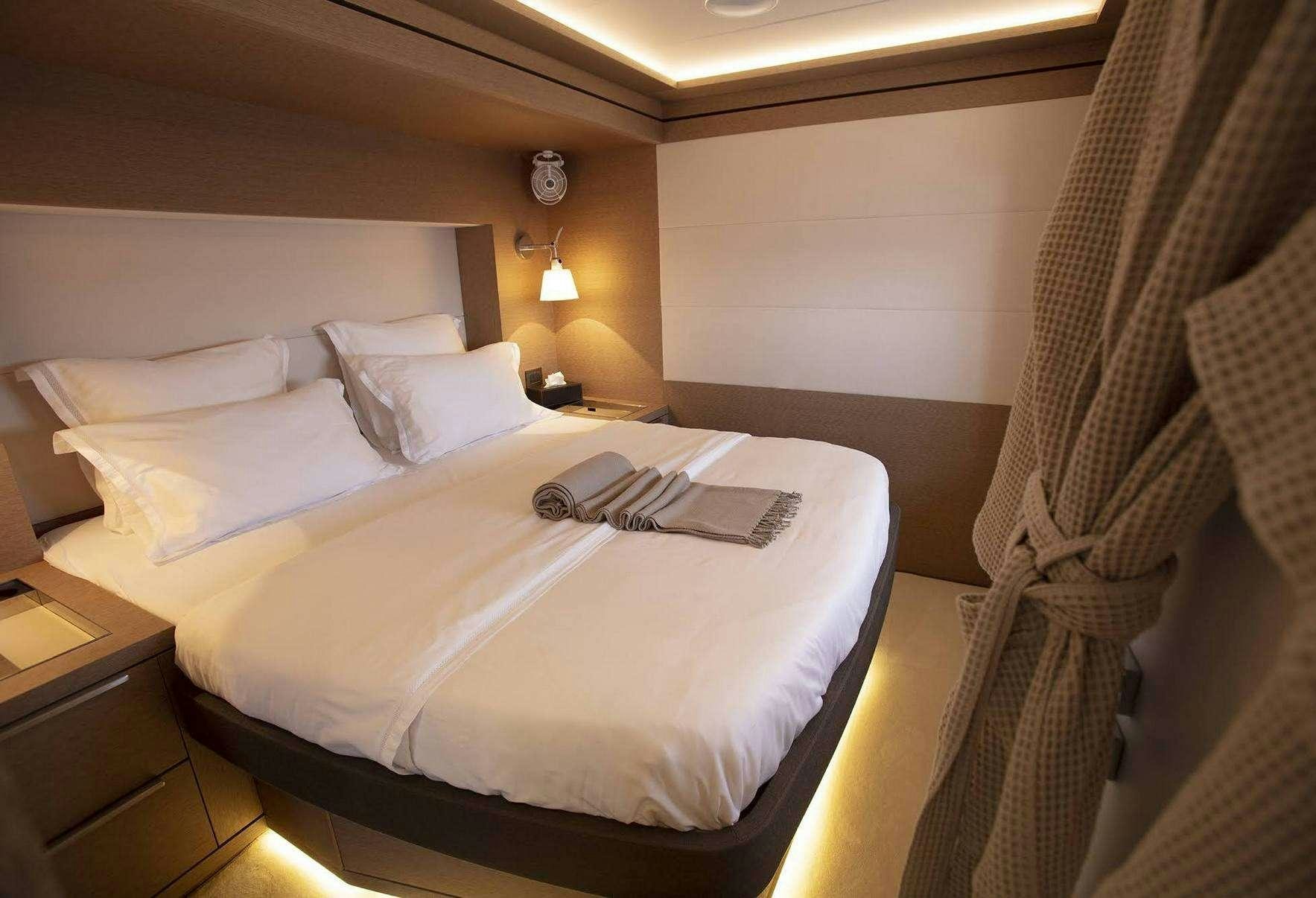 a bed with a white sheet and a white pillow on it aboard BABAC Yacht for Charter