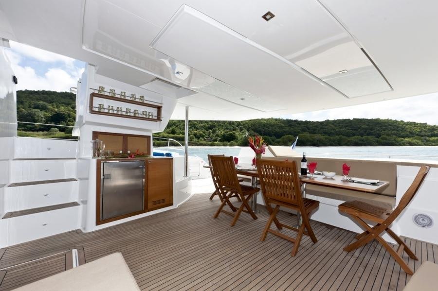 a room with a table chairs and a kitchen with a large window aboard ALIVE Yacht for Charter