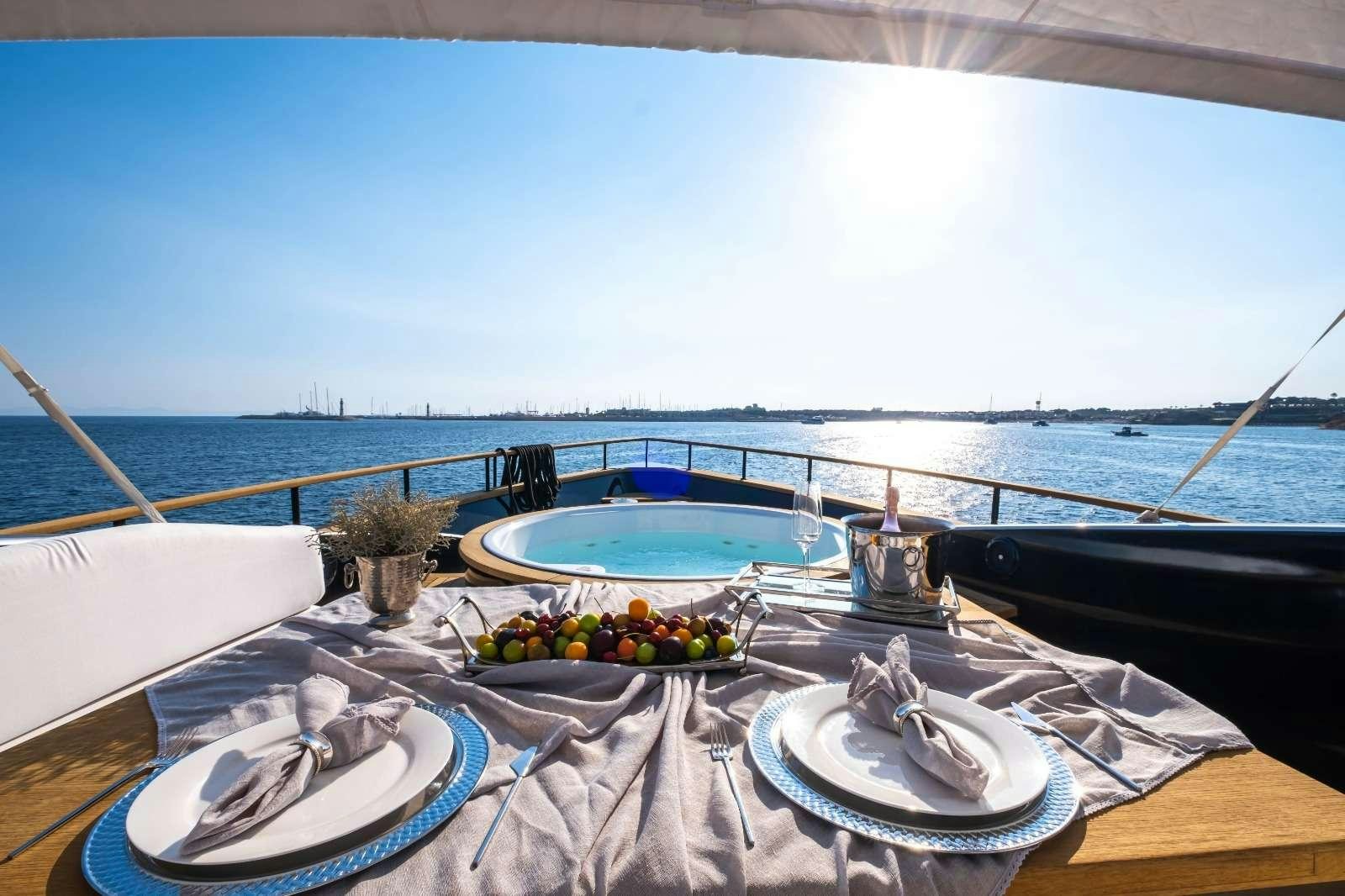 a table with a bowl of fruit on it and a view of the ocean and the ocean aboard HARUN Yacht for Charter