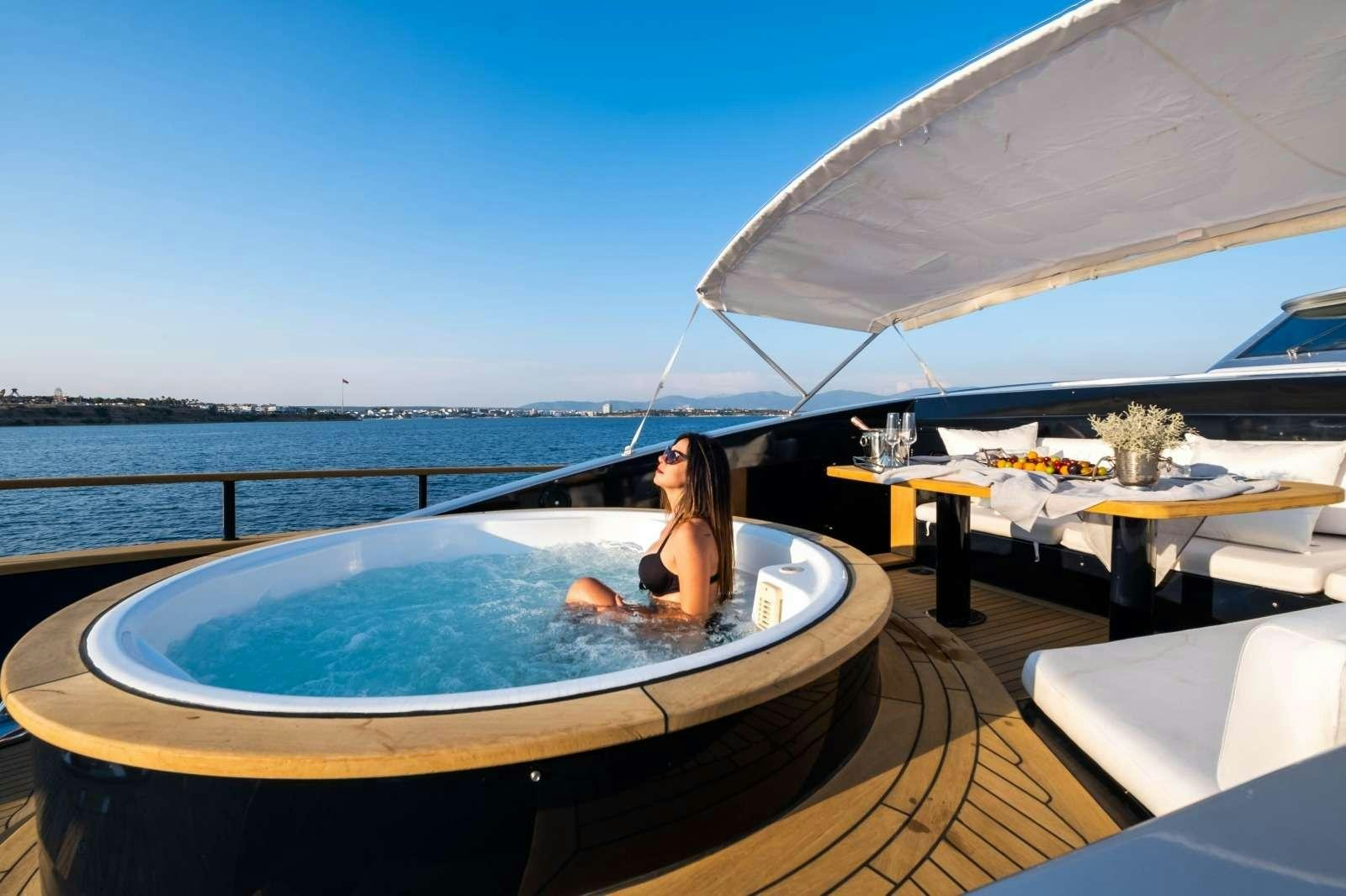 a person sitting in a hot tub on a deck overlooking the ocean aboard HARUN Yacht for Charter