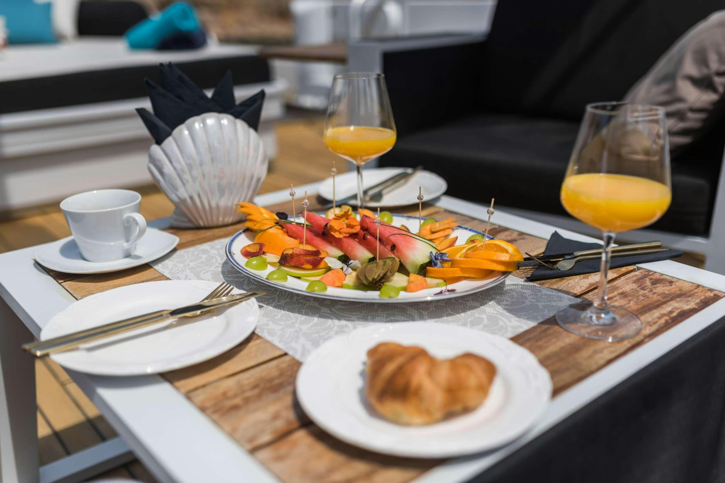 a table with plates of food and glasses of juice aboard BORA BORA Yacht for Charter
