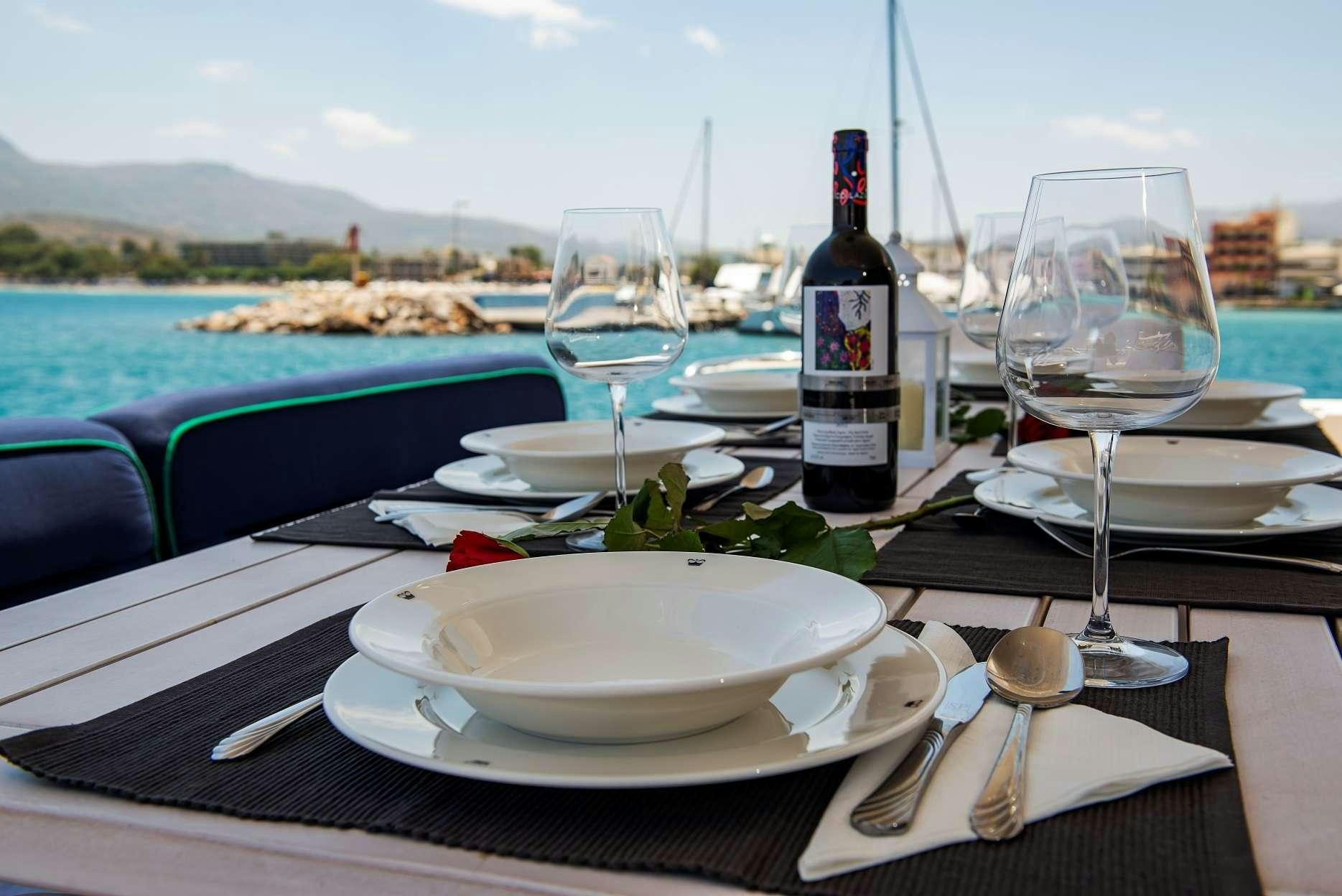 a table with a wine bottle and plates on it aboard VENALI Yacht for Charter