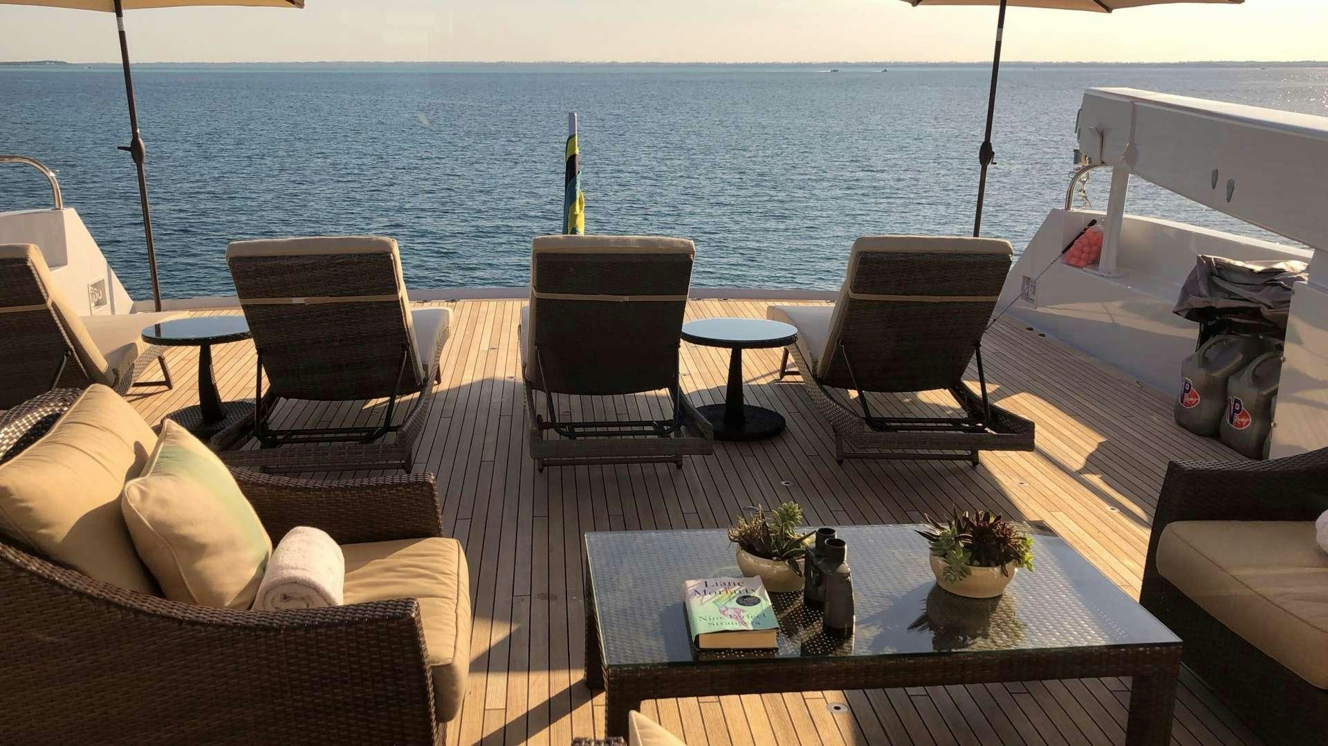 a deck with chairs and tables on it by the water aboard CHERISH Yacht for Charter