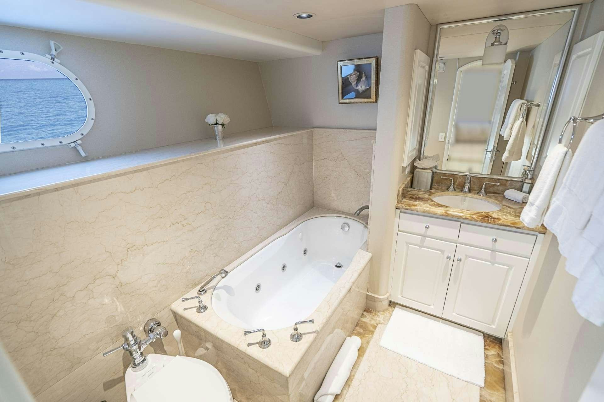 a bathroom with a tub sink and a mirror aboard CHERISH Yacht for Charter